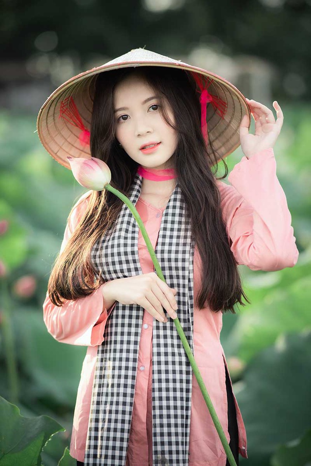 Thiếu nữ xinh đẹp từ đất Hà Nội đang cầm trên tay những cánh hoa sen tượng trưng cho sự thuần khiết. Bức ảnh sẽ mang đến cho bạn cảm giác thanh tao và yên bình trước vẻ đẹp đơn giản của hoa sen.