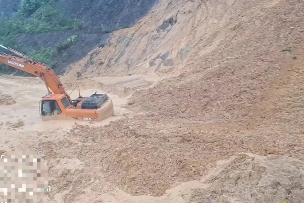 Bùn đất từ đồi bất ngờ đổ ập xuống vùi máy múc, tài xế thoát nạn - Hình 1