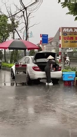 Hành động lạ bên cạnh chiếc ô tô của người phụ nữ bán nước dưới cơn mưa nặng hạt khiến dân mạng đứng hình - Hình 1